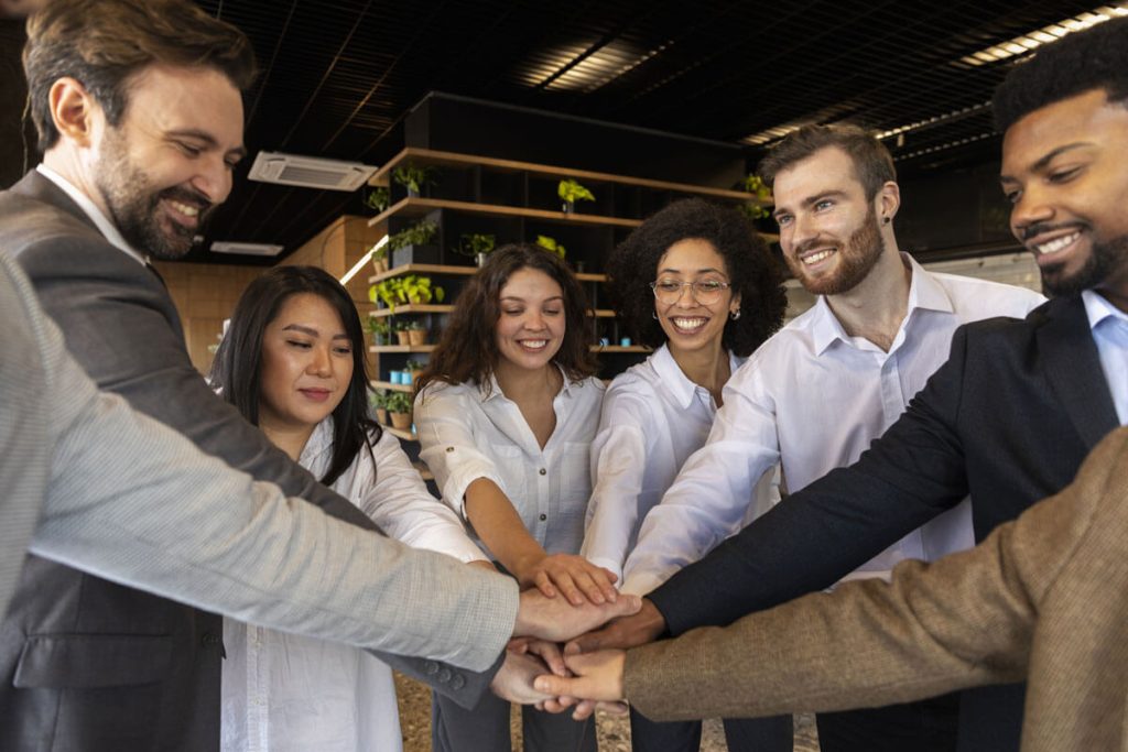 8 estratégias para otimizar seu time de vendas Equipe juntando as mãos para comemorar trabalho em equipe na Weein agência de marketing digital