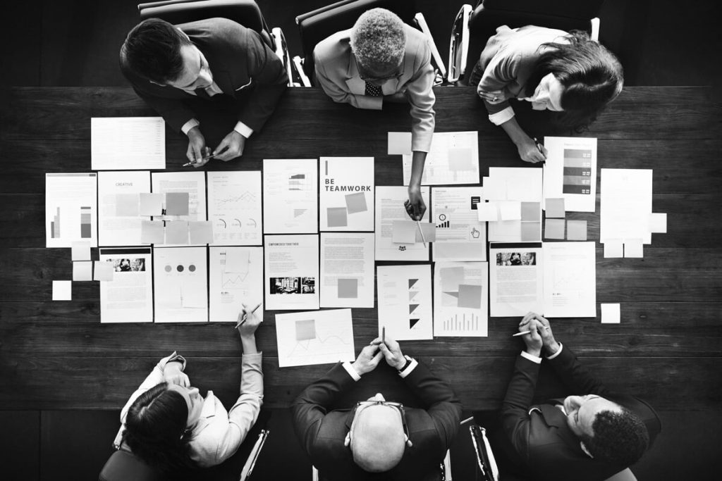 venda-sem-depender-de-trafego-pago-capa-weein-agencia-de-seo-estrategico-ot Mesa quadrada com papeis em cima, onde 6 especialistas em redação e SEO discutem