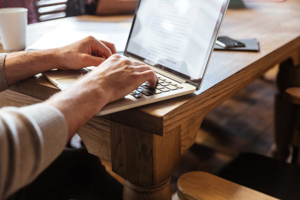 produzir-artigos-para-ter-resultado-com-seo-capa-weein-agencia-de-seo-estrategico-ot Pessoas na mesa com notebook escrevendo artigos focados em seo
